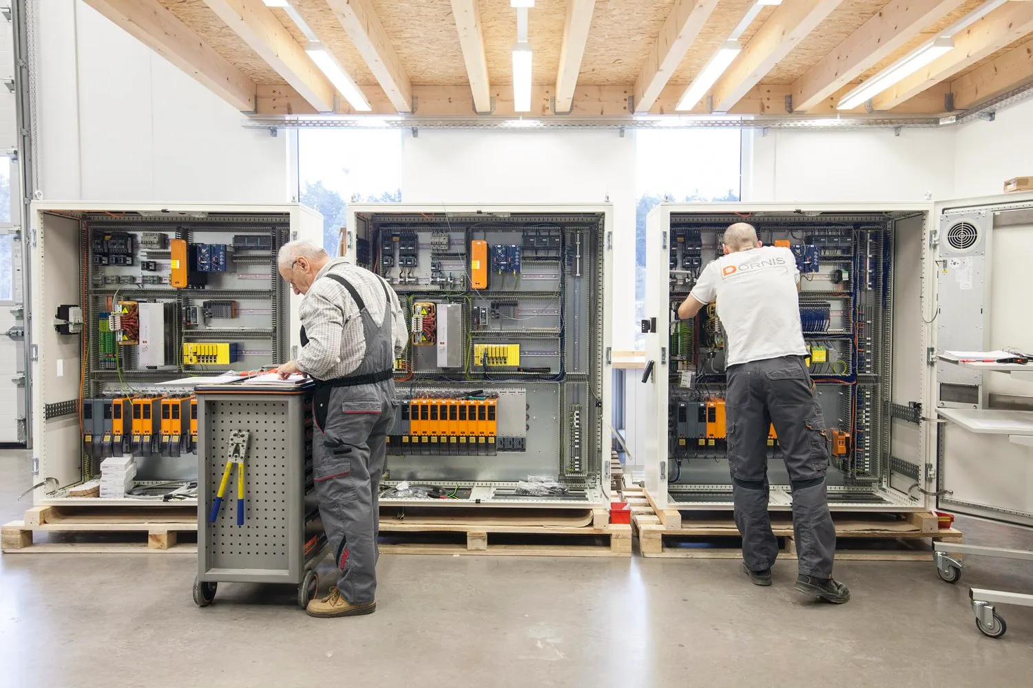 Zwei Mitarbeiter beim Aufbau großer Schaltschränke in der DORNIS Werkhalle